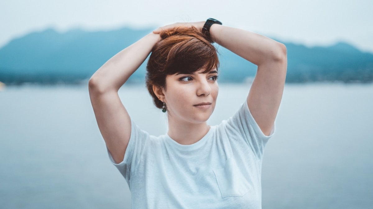 woman in white crew neck t-shirt holding her hair